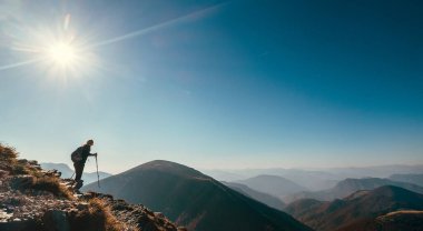 Güneş ışığı altında dağ tepesinde gezgin bir gezgin.