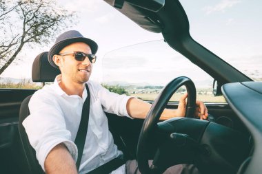 Cabriolet araba kullanan bir adam dağ yolundan geçiyor. Araba manzaralı.