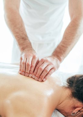 Sakallı masör, genç kadın vücut masajı sırasında boyun omurga bölgesinde masaj manipülasyonları yapıyor. Osteokondrosis önleme konsepti görüntüsü.