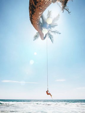 Mutlu küçük çocuk tropikal palmiye ağacında sallanıyor. Dikkatsiz mutluluk konsepti imajı.