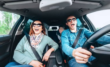  Neşeli genç geleneksel aile uzun bir araba yolculuğuna çıkıyor ve birlikte yüksek sesle en sevdiği şarkıyı söylüyor. Güvenli sürüş konsepti geniş açılı araç görüntüsü. 