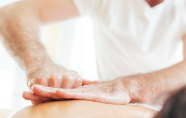 Masörün erkek elleri, genç kadın vücut masajı sırasında Scapula bölgesinde masaj manipülasyonları yapıyor..