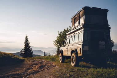 Off-road 4x4 Slovakya Dağları 'ndaki kirli köy yolunda sabah erken saatlerde yüksek çatılı uyku çadırı depolama aracı.