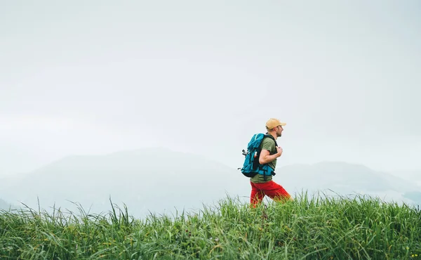 徒步旅行者背着背包走在多雾多云的天气山脉小径上的侧拍 积极运动背包健康生活方式的概念 — 图库照片