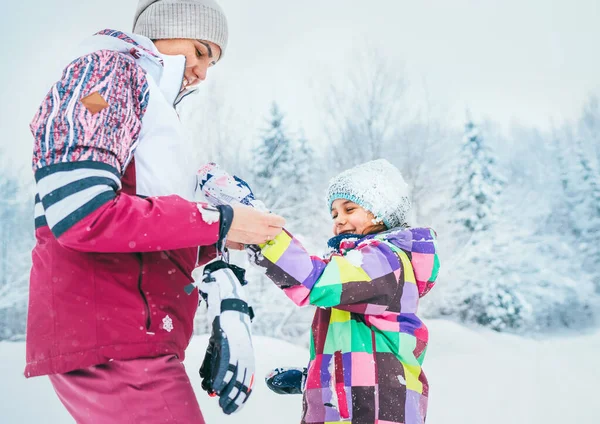 在雪地的森林散步时 妈妈帮她的小女儿戴着温暖的手套 — 图库照片