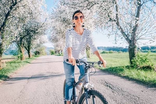 Щаслива Усміхнена Жінка Їде Велосипеді Сільській Дорозі Під Квітучими Деревами — стокове фото