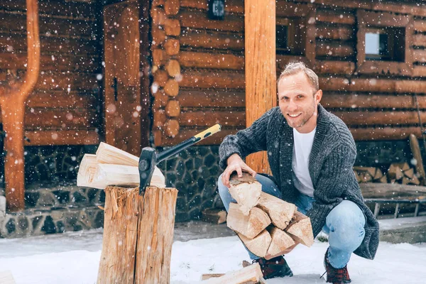 豪雪の背景を持つ家の暖炉のために雪の庭で木を切る男 冬の田舎の休日のコンセプトイメージ — ストック写真