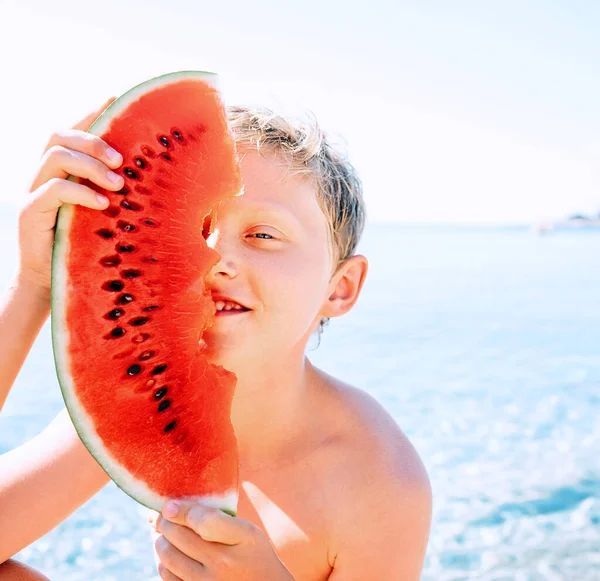 Szczęśliwy Uśmiechnięty Chłopiec Dużym Segmentem Arbuza Siedzi Pobliżu Morza — Zdjęcie stockowe