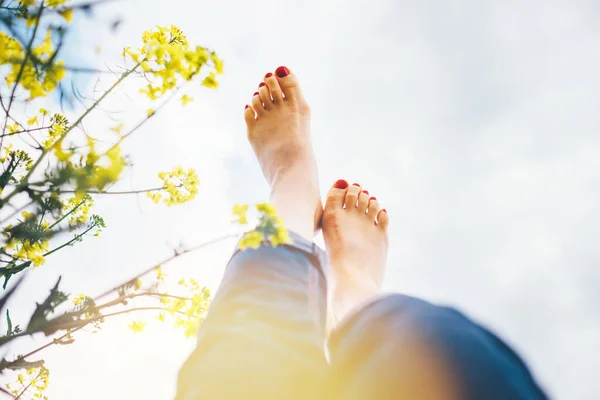 明るい晴れた日の光太陽がフレアをビームと深い黄色の花の牧草地に横たわって幸せな女性の脚を 自然コンセプトでの幸福 Pov画像 — ストック写真