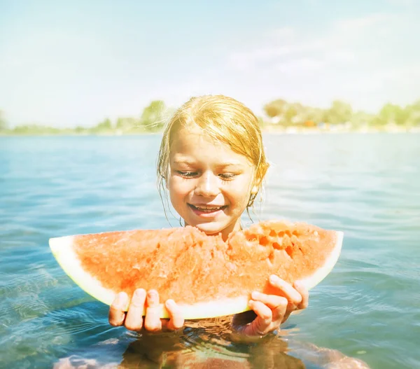 小さな笑顔女の子食べる赤いスイカの肖像画上の夏の川 — ストック写真