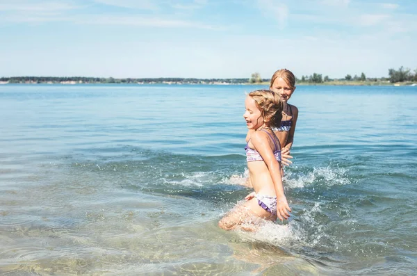 两个妹妹在平静的海浪中嬉戏 互相泼水 家庭度假概念形象 — 图库照片