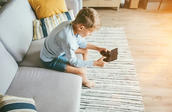 十几岁的男孩沉迷于电脑游戏 坐在舒适的沙发上 用智能手机做游戏垫 — 图库照片
