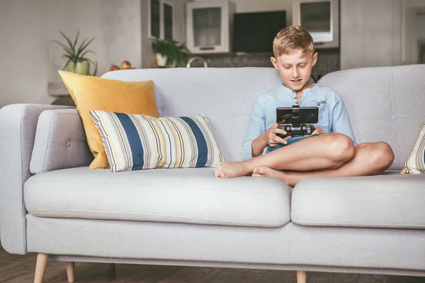 コンピュータゲームで迷子になった18人の少年 ソファの上に家に座って スマートフォンでゲームパッドを使用しています — ストック写真