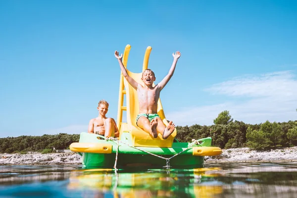 Malý Chlapec Sklouzává Mořské Vody Plovoucího Hřiště Skluzavka Katamarán Jak — Stock fotografie