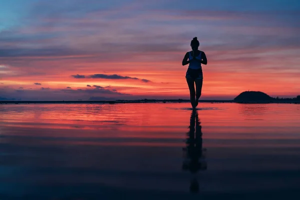 女子在夕阳西下的海滩上沉静地做瑜伽冥想 — 图库照片