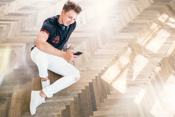 Joven Hombre Usando Teléfono Inteligente Con Auriculares Escuchar Música Sentarse — Foto de Stock