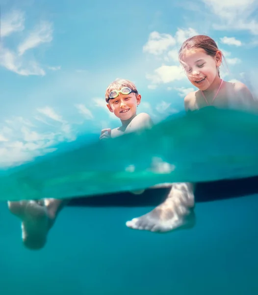姐妹俩坐在充气的床垫上 享受海水 在海里游泳时开怀大笑 漫不经心的童年假期不同寻常地不可用相机拍摄图像 — 图库照片