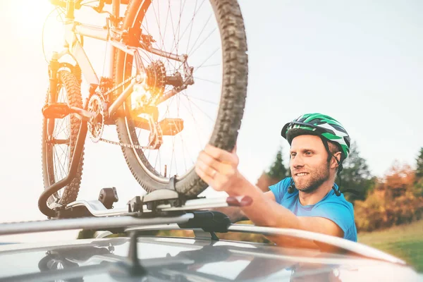 サイクリスト男は車の屋根の上に彼の自転車に保持します — ストック写真