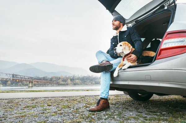 Sıcak Giysiler Içinde Bagajında Bir Köpekle Oturan Damızlık Bir Adam — Stok fotoğraf