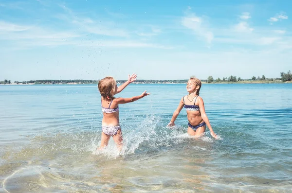 两个妹妹在平静的海浪中嬉戏 互相泼水 家庭度假概念形象 — 图库照片