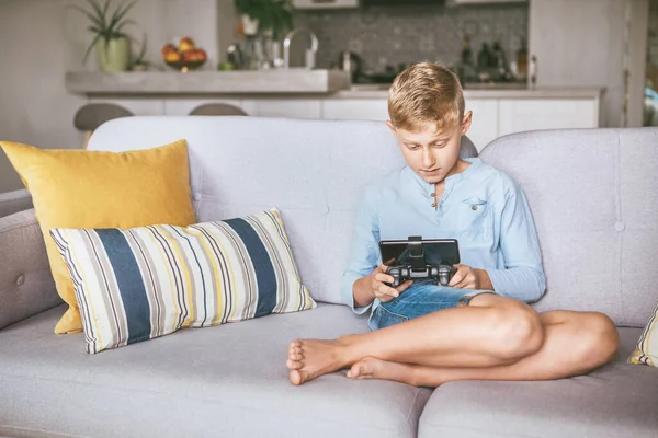 十几岁的男孩沉迷于电脑游戏 坐在舒适的沙发上 用智能手机做游戏垫 — 图库照片
