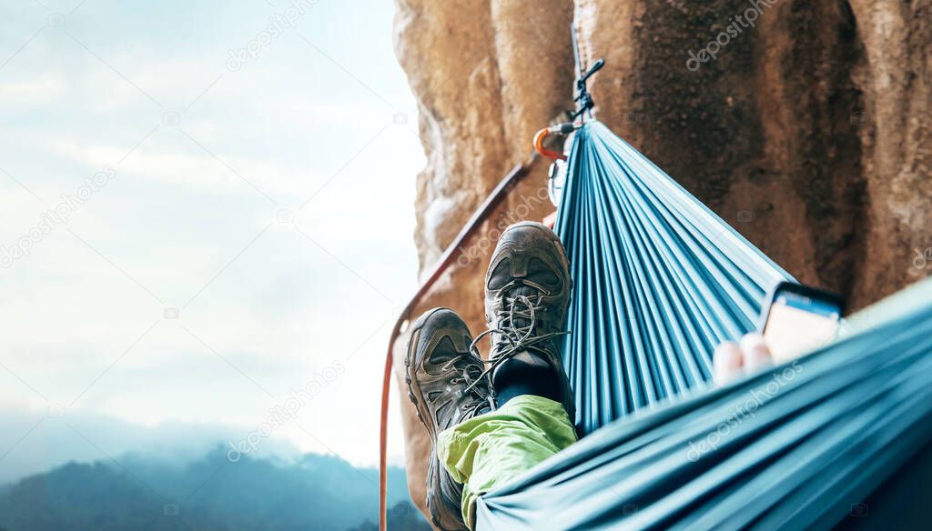 Climber resting in hammock on the vertical cliff wall