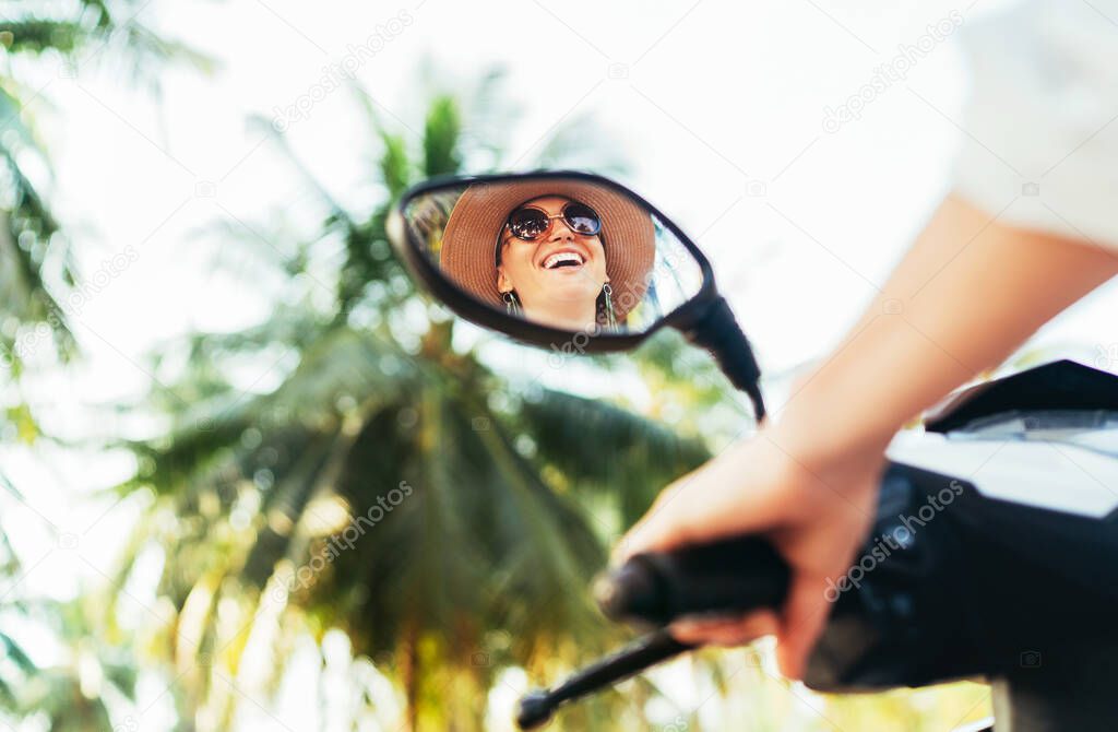 Happy smiling traveller woman riding Scooter motorbike in back mirror reflection