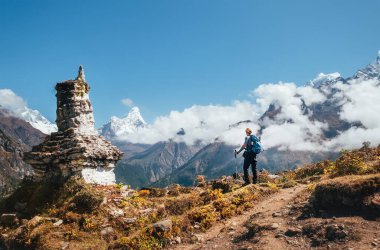 Ama Dablam 6814m zirvesinin keyfini çıkaran yürüyüş direkleri olan genç bir gezgin, Budist stuphisi yakınlarında iklim yürüyüşü yapıyor. Everest Kampı güzergahı, Nepal. Etkin tatil konsepti resmi