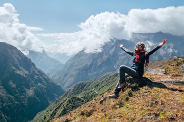 Genç yürüyüşçü kadın kollarını kaldırıyor, neşeyle gülüyor ve Nepal yakınlarındaki yüksek irtifa Everest Ana Kampı (EBC) yürüyüş rotasında vadinin tadını çıkarıyor. Etkin tatil konsepti resmi.