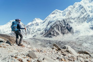 Yürüyüşte fren yapan genç gezgin bayan Khumbu Buzulu 'nun tadını çıkarıyor. Gorakshep, Nepal yakınlarındaki Everest Ana Kampı rotasında. Arka planda Nuptse 7861 metre. Etkin tatil kavramı