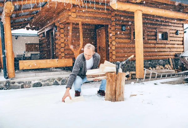 人们在雪地的院子里砍柴 找一个有厚厚的雪片背景的房子生火 冬季乡村假日的概念形象 — 图库照片