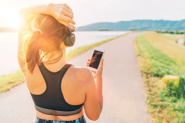 Young Female Starting Jogging Listening Music Using Smartphone Wireless Headphones — Stock Photo, Image
