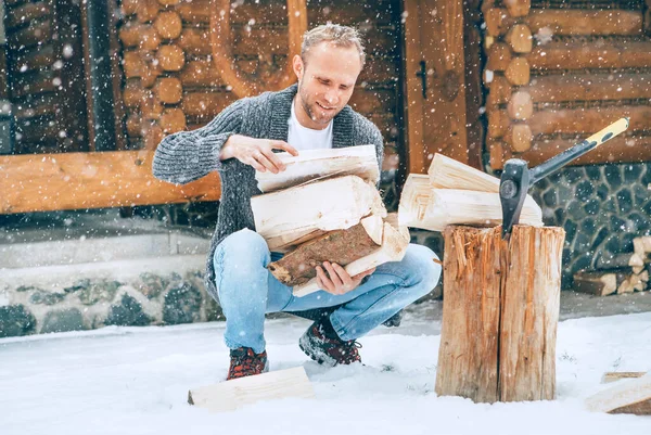 豪雪の背景を持つ家の暖炉のための雪の庭にみじん切り薪を収集する男 冬の田舎の休日のコンセプトイメージ — ストック写真