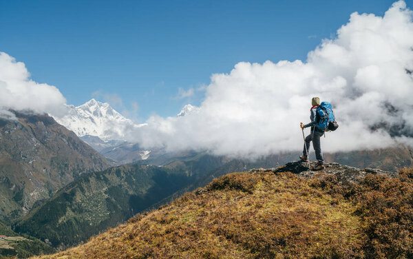 Young hiker backpacker man using trekking poles enjoying the Nuptse 7861m mountain during high altitude Acclimatization walk. Everest Base Camp trekking route, Nepal. Active vacations concept image