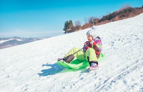 雪の斜面から滑り降りて幸せな笑いの少女 面白い冬の休日のコンセプトイメージを過ごす — ストック写真