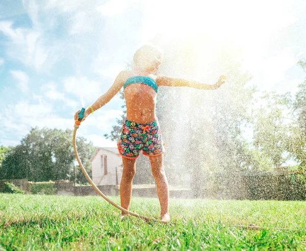 かわいい女の子は庭の散水ホースから自分自身をリフレッシュ — ストック写真