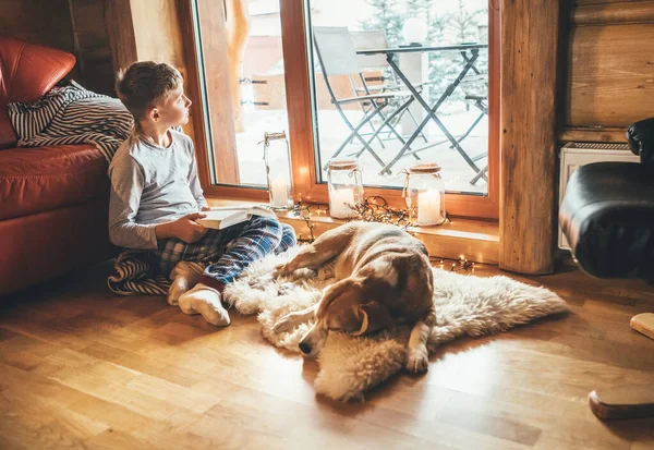 居心地の良い家庭的な雰囲気の中で羊の皮に彼のビーグル犬を滑らせる近くの床の上に少年読書本 居心地の良い家庭のコンセプトイメージの静かな瞬間 — ストック写真
