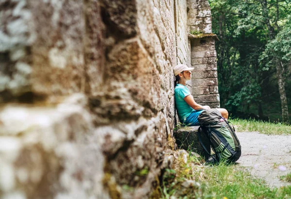 Unavená Žena Batohem Odpočívá Lavičce Blízkosti Staré Starožitné Zděné Zdi — Stock fotografie