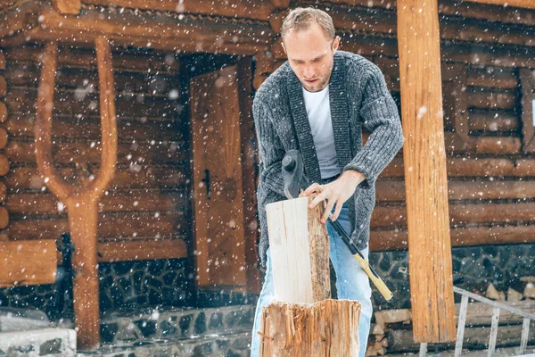 豪雪の背景を持つ家の暖炉のために雪の庭で木を切る男 冬の田舎の休日のコンセプトイメージ — ストック写真