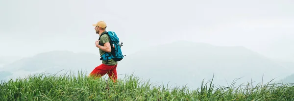 徒步旅行者背着背包走在多雾多云的天气山脉小径上的侧拍 积极运动背包健康的生活方式的概念 网站标题裁剪 — 图库照片