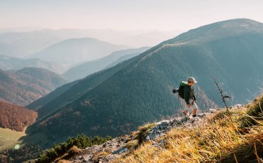 Küçük Çocuk sırt çantalı gezgin High Tatra dağlarında dağın tepesinde yürüyor.