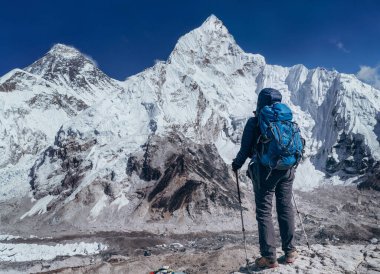 Yürüyüşte fren yapan genç gezgin bayan Khumbu Buzulu 'nun tadını çıkarıyor. Gorakshep, Nepal yakınlarındaki Everest Ana Kamp rotası. Everest Tepesi 8848 metre (solda) ve Nuptse 7861 metre (sağda) arkaplanda. 