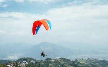 Nepal, Pokhara 'da renkli bir paraglider kullanarak eğitmenle paraşütle atlamak. Etkin tatil konsepti resmi.