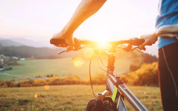 男子手扶着自行车方向盘 把画面拉近 骑自行车的人呆在山顶上欣赏日落 — 图库照片