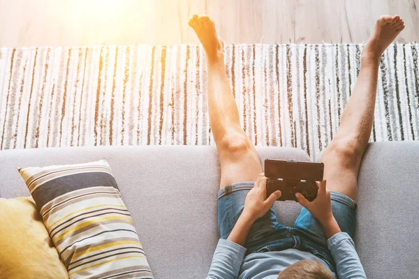 Junge Sitzt Auf Sofa Und Spielt Mit Smartphone Und Gamepad — Stockfoto