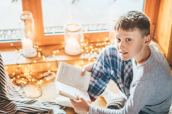 居心地の良い家庭的な雰囲気の中で羊の皮の上の床の上に少年読書本 居心地の良い家庭のコンセプトイメージの静かな瞬間 — ストック写真