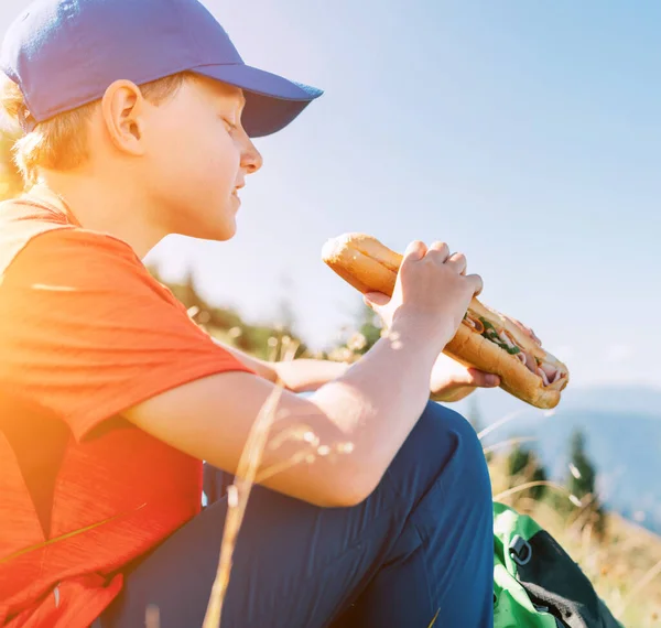在山路食物断点上 带着巨大的长面包三明治 微笑着男孩的肖像 — 图库照片
