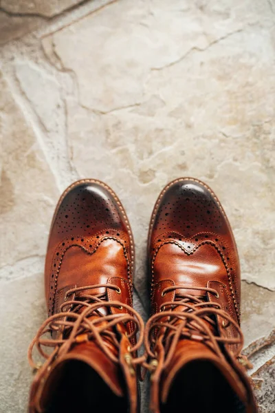 天然石の床の上に立つ未配置の靴ひもを持つブラウンナチュラルレザーミディアムブーツのペアビュー — ストック写真