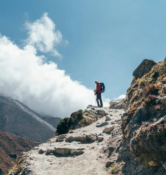登山者在云彩背景上的人物形象站在穿过Imja Khola山谷的小径上 在登博什附近的珠穆朗玛峰基地徒步旅行途中欣赏山景 积极休假形象 — 图库照片
