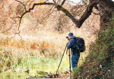Tripod kullanan profesyonel fotoğrafçı, Hırvatistan 'ın Plitvice Lakes Ulusal Parkı' ndaki sonbahar göllerinin fotoğrafını çekti.